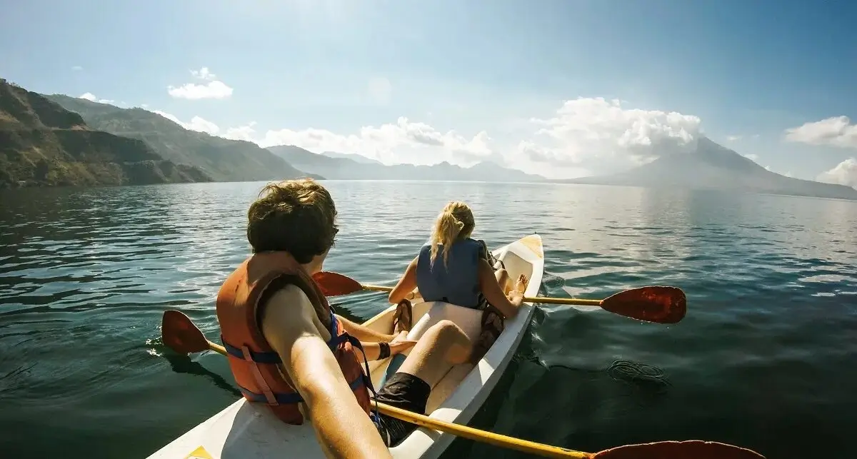 Couple kayaking in a crystal clear lake surrounded by mountains
