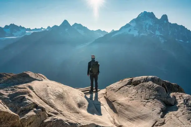 Hiker standing on a mountain peak looking at a stunning valley below