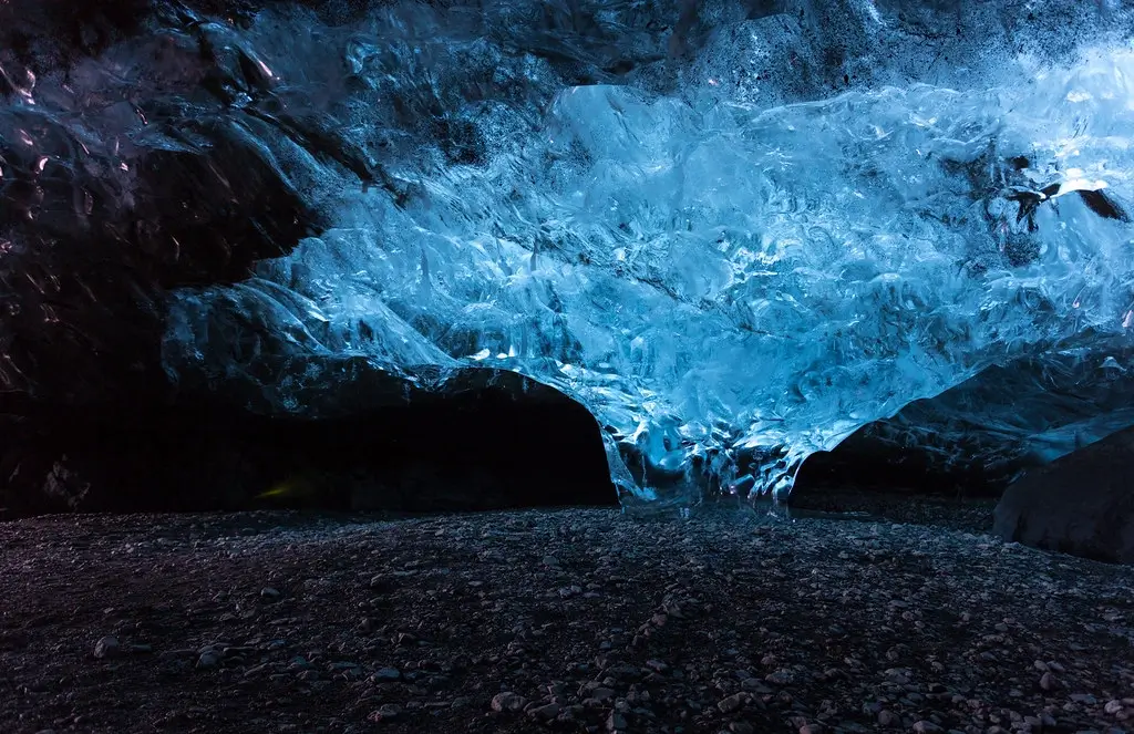 Dramatic ice cave in Iceland with blue light shining through