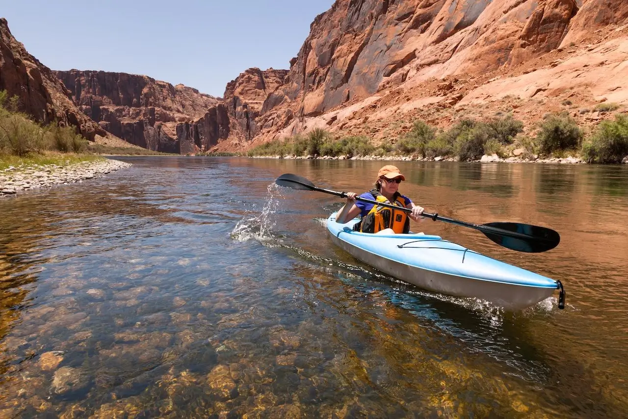 People kayaking in a clear blue river canyon