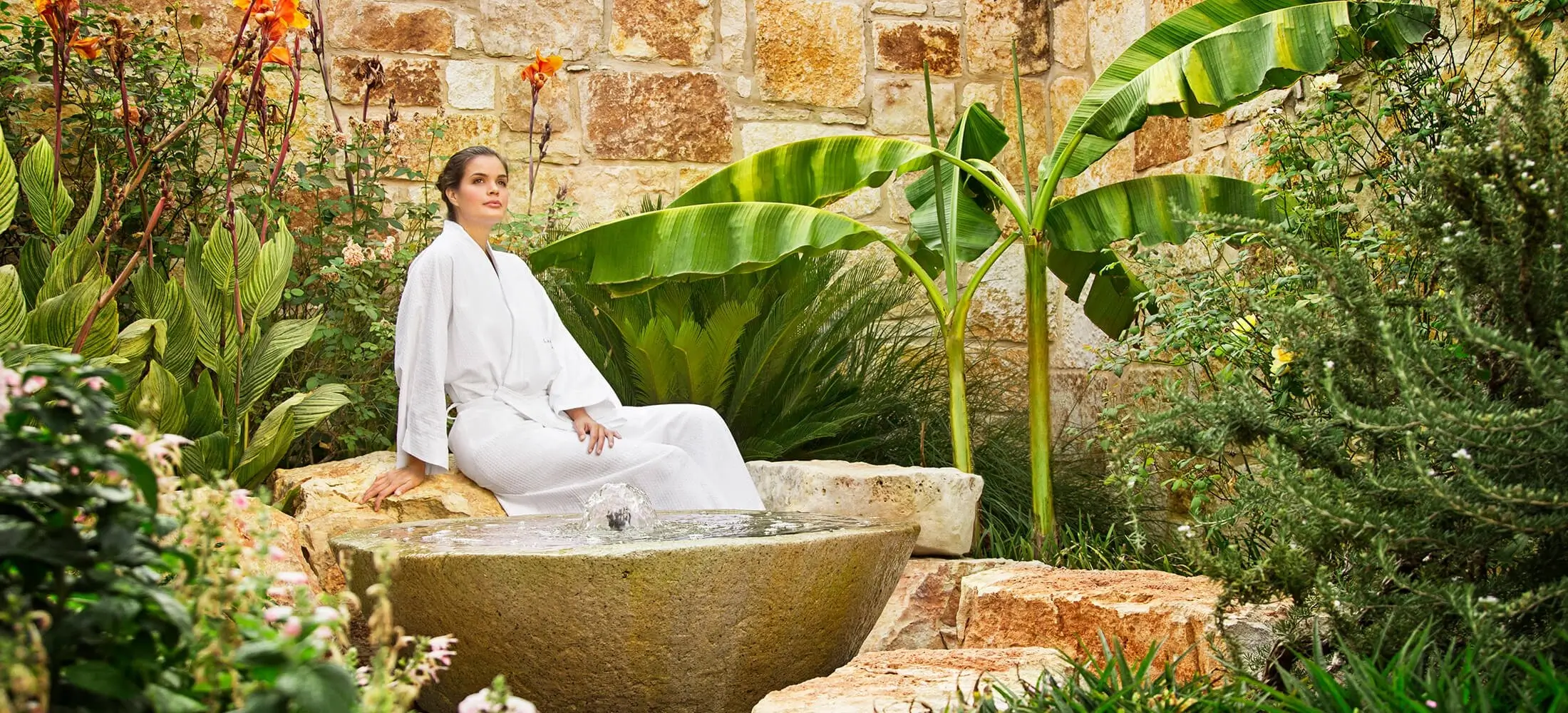 A person relaxing in a spa with a view of a tropical garden
