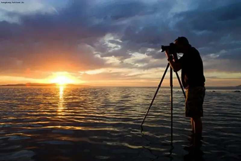 Person taking a photo of a sunset with a professional camera